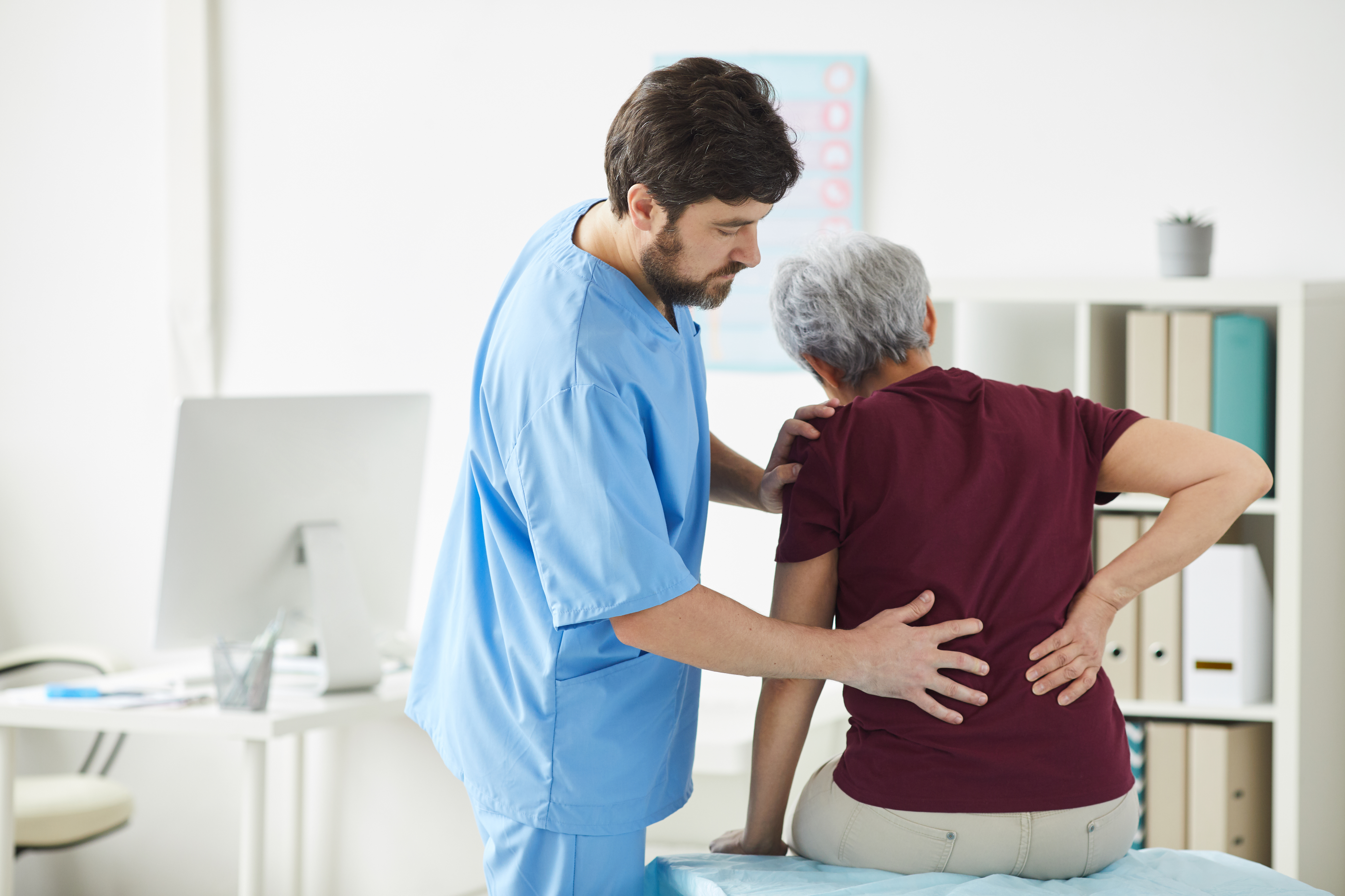 Physiotherapist assessing a patient's lower back